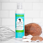 Bottle of Crenshaw Rose coconut water leave-in detangling hair treatment with coconuts and a whisk on a white background.