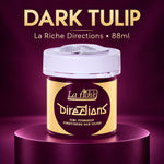 A jar of La Riche Directions 'Dark Tulip' semi-permanent conditioning hair color, displayed on a metallic purple pedestal against a matching purple background. The product packaging features a gold label with a dark purple circle and a white screw cap.