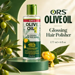 A bottle of ORS Olive Oil Glossing Hair Polisher stands on a green pedestal, surrounded by olive branches and olives, with large product text on a cream and green background.