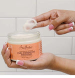 Person applying hair product from a jar with a tiled background